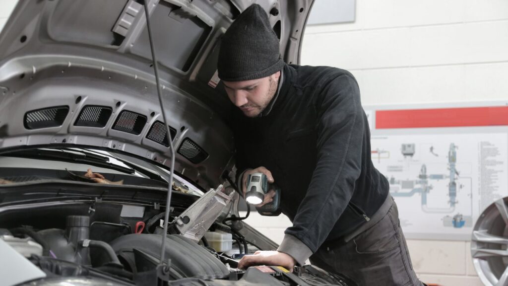 Technician inspecting a car engine during a pre-purchase vehicle inspection.