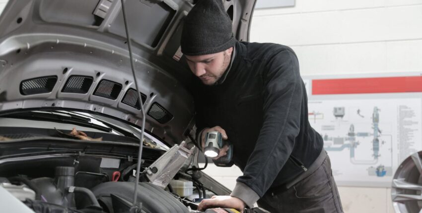 Technician inspecting a car engine during a pre-purchase vehicle inspection.
