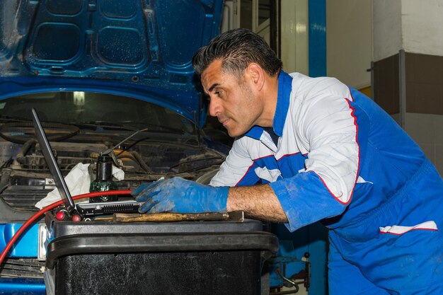 Automotive mechanic inspecting car engine in garage setting.