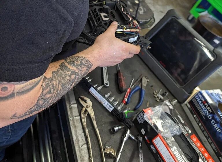 Technician performing engine diagnostics with advanced tools at Catalpa Street Garage.