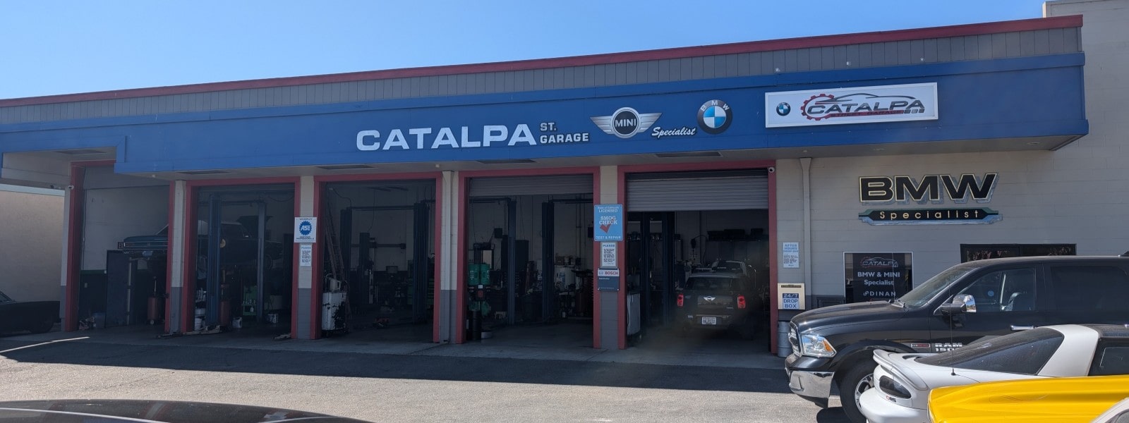 Exterior view of Catalpa Street Garage with multiple service bays and a BMW vehicle.