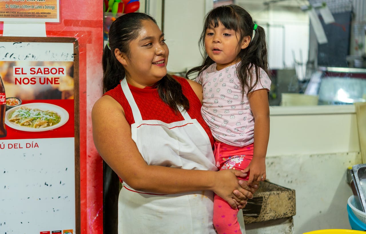 A smiling woman holding her daughter at a local market in Ciudad de México, Mexico.