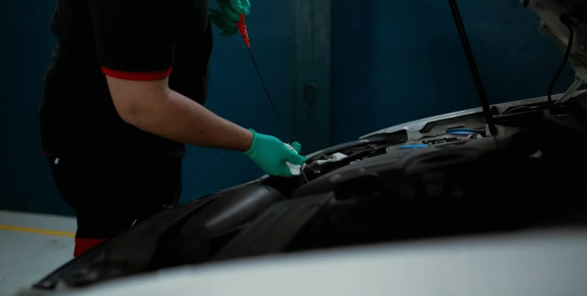 Technician checking engine oil level during car maintenance at Central Texas Qwiklube.