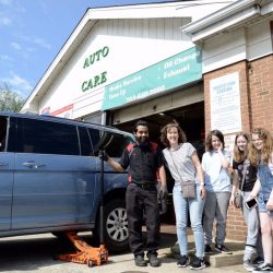 Auto repair shop with a technician and students outside, emphasizing modern auto care services.