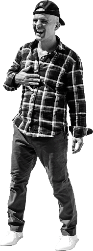 A man enjoying beer, smiling and dressed casually, standing outdoors in a lively, relaxed atmosphere.