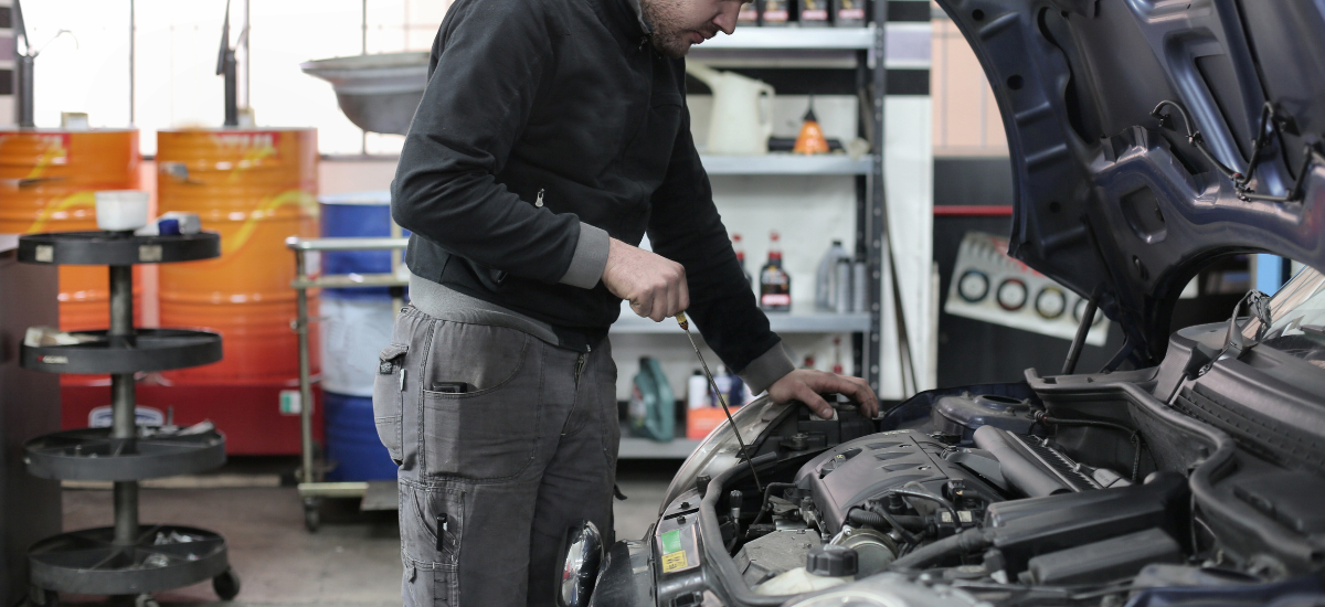 Auto mechanic inspecting car engine in repair shop.
