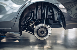Car with removed wheel showing brake and suspension system.