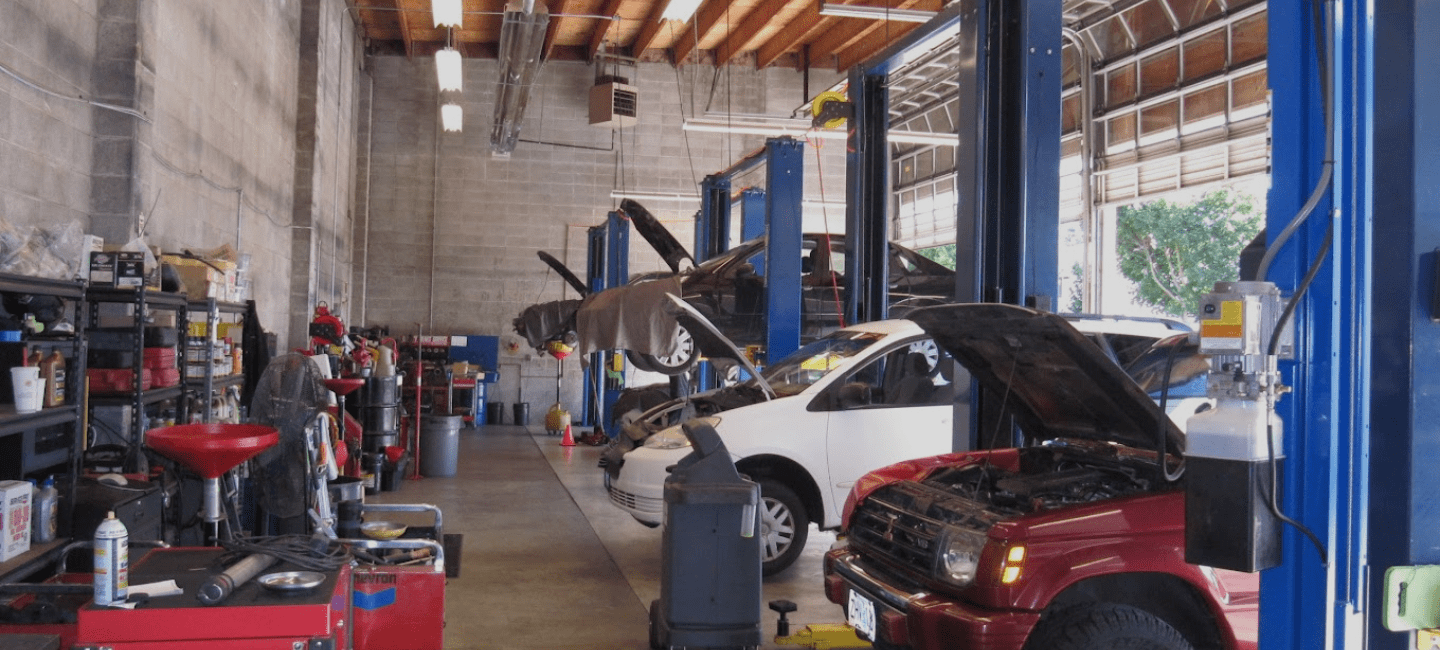 Auto repair shop with multiple vehicles being serviced and repaired inside a spacious garage.