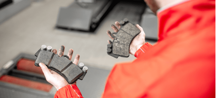 Technician inspecting brake pads during repair at Clay's Auto.
