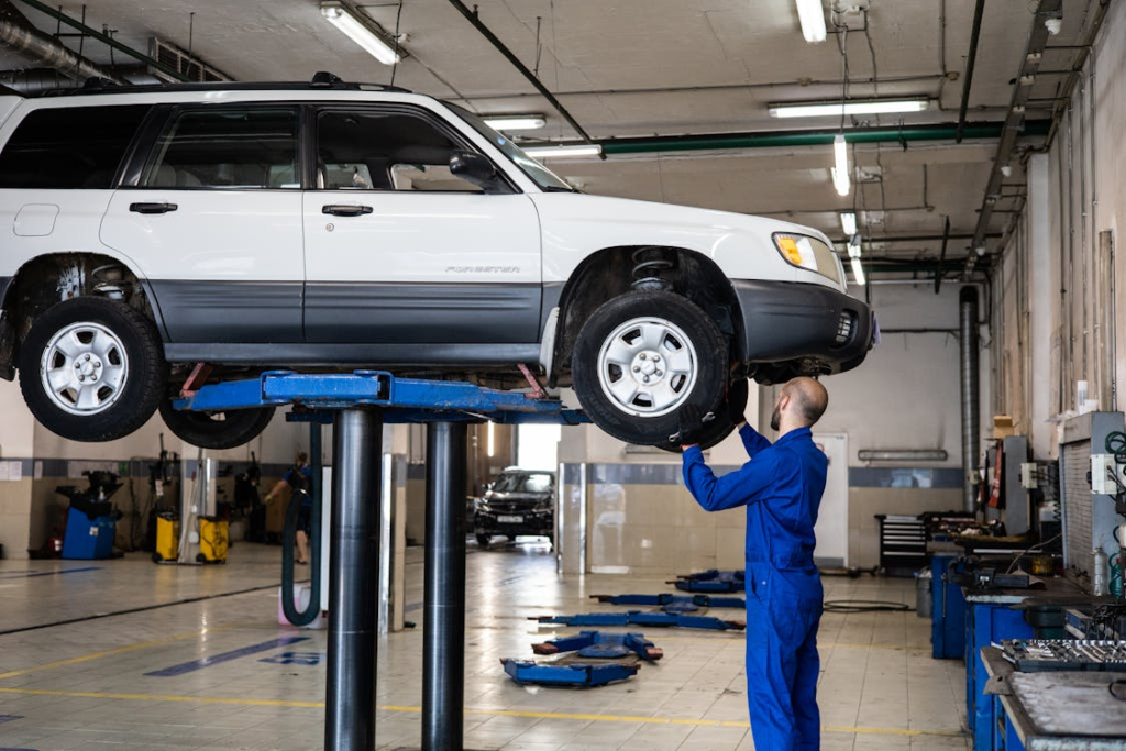 Auto repair technician inspecting a vehicle on a lift at Clay’s Auto Service.