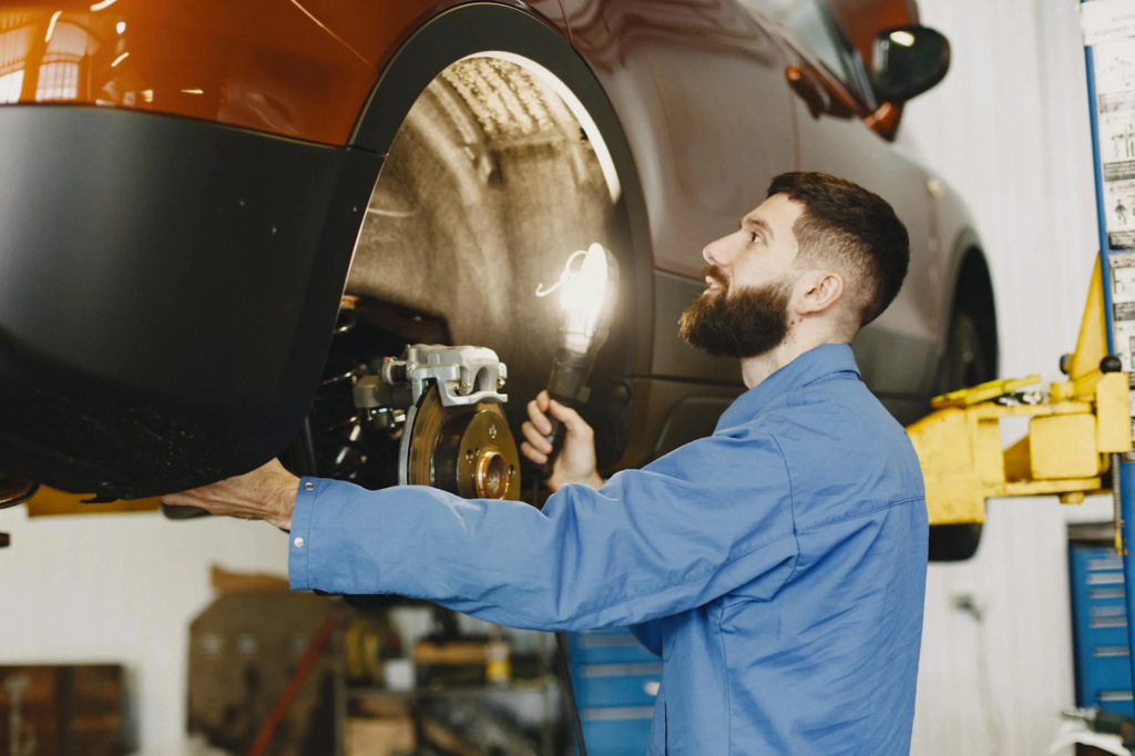 Auto mechanic inspecting brake system on a vehicle in the workshop.