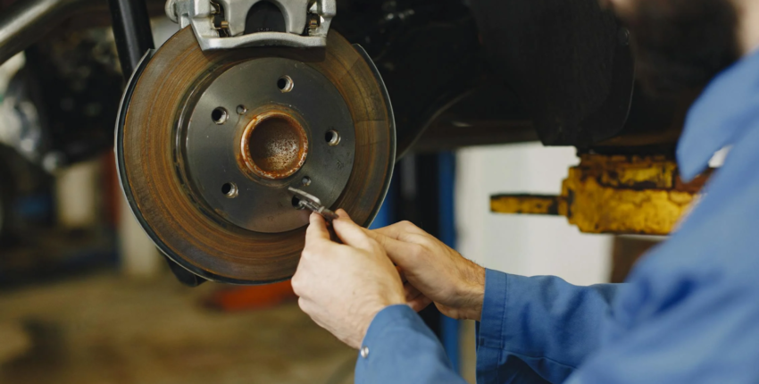 Technician inspecting a vehicle's brake disc for wear and damage.