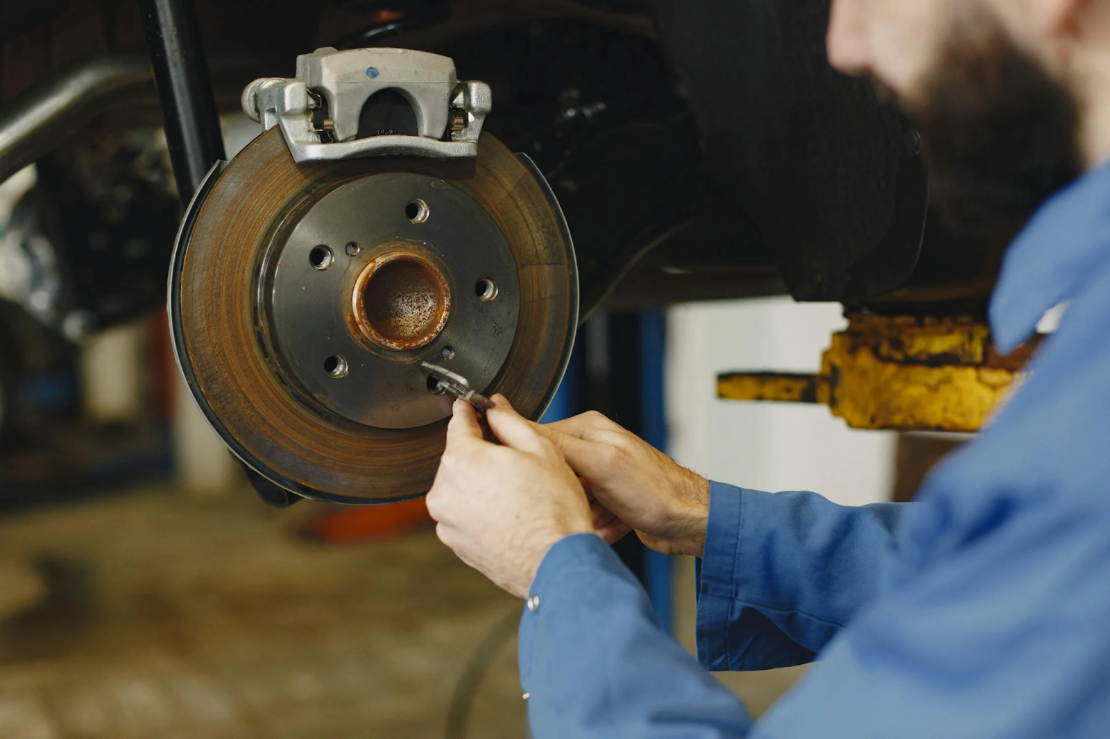 Technician inspecting a vehicle's brake disc for wear and damage.