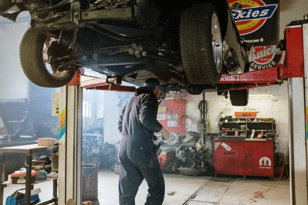 Auto repair technician inspecting a car lifted for maintenance and repairs.