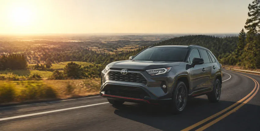 Toyota RAV4 SUV driving on a scenic road during sunset.
