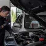 Auto mechanic inspecting engine under the hood at Clay's Auto.