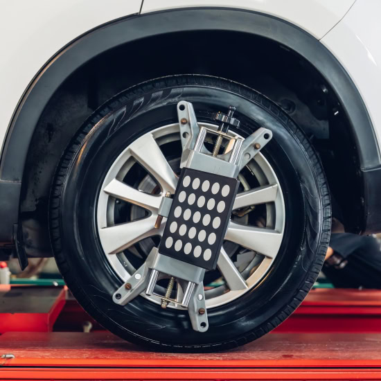 Automotive wheel with balancing weights and equipment in service shop.