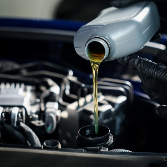 Pouring new oil into a car engine during maintenance.