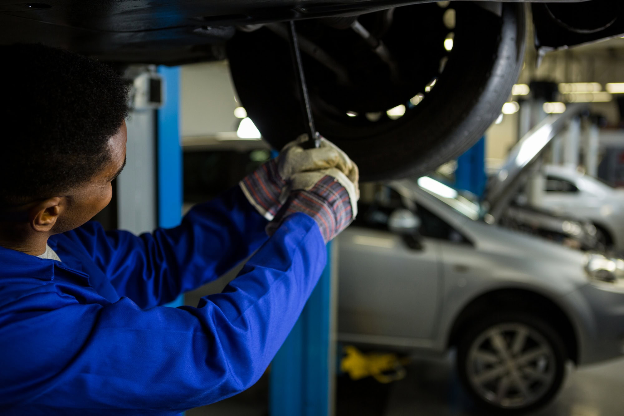 Technician performing brake fluid flush on vehicle in auto repair shop.