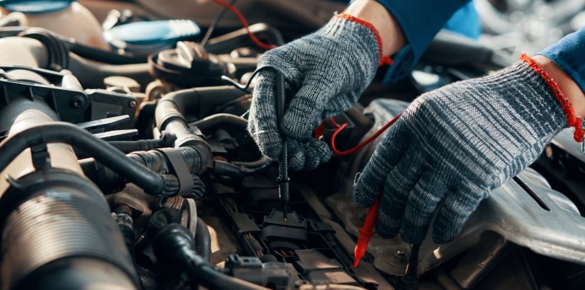 Skilled technician performing engine repair with tools and gloves at Cor's Motors.