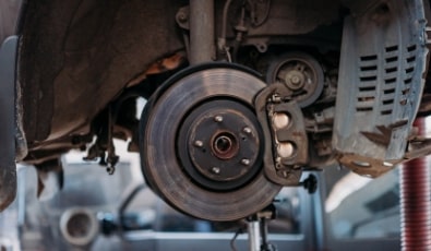 Close-up of a car brake disc and caliper at Cor's Motors Auto Repair shop.