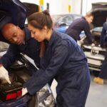Experienced technicians inspecting a vehicle engine in a professional auto repair shop.