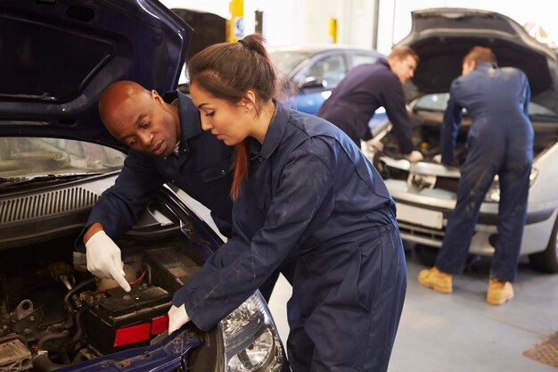 Experienced technicians inspecting a vehicle engine in a professional auto repair shop.
