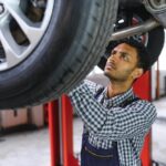 Technician inspecting vehicle tire at auto repair shop.