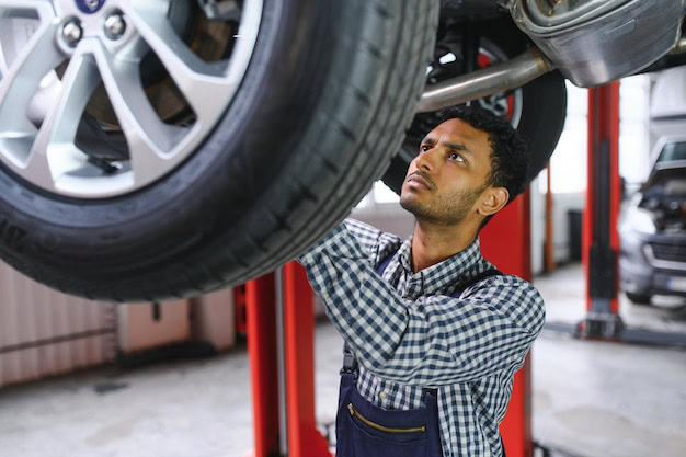 Technician inspecting vehicle tire at auto repair shop.