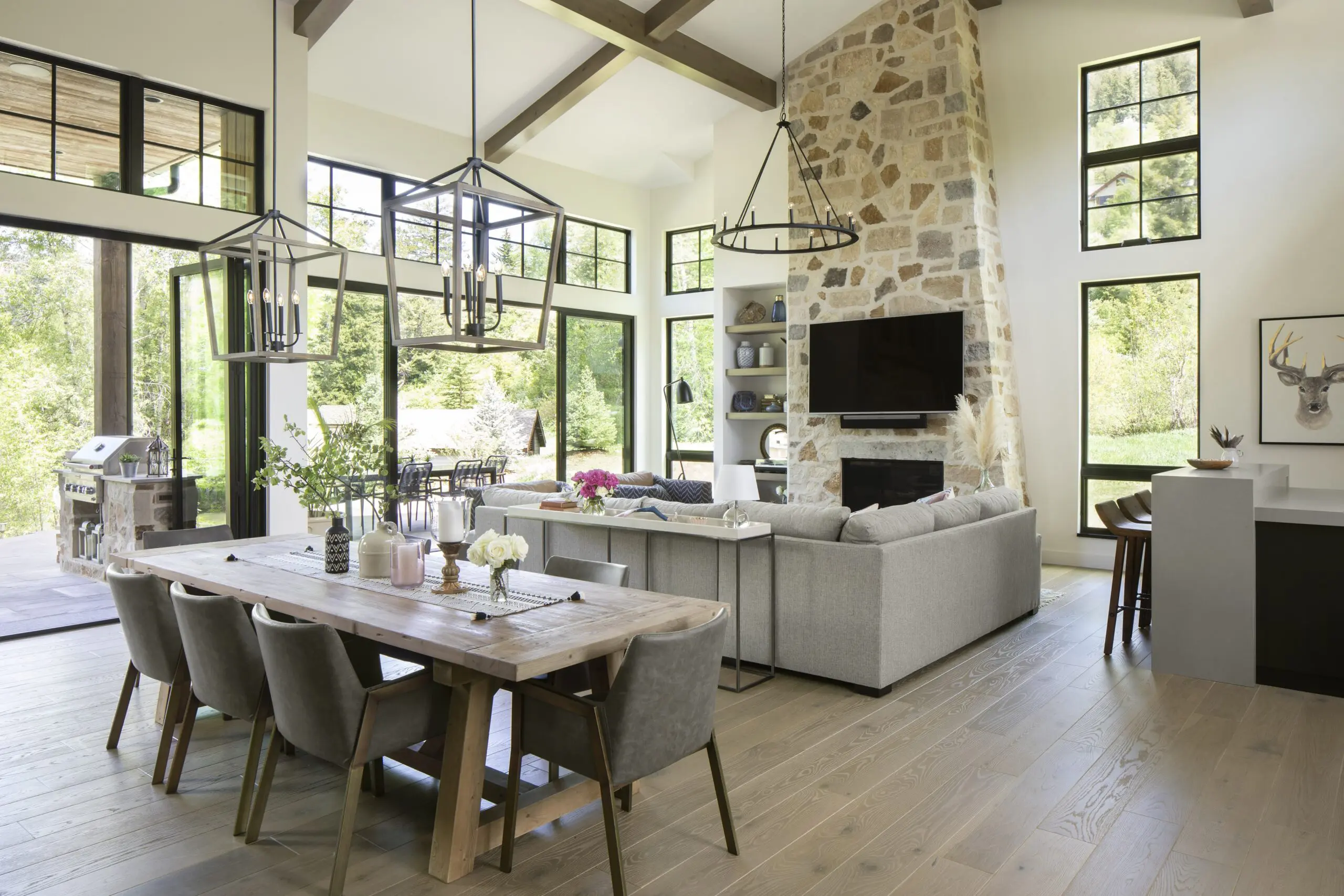 Warm wood flooring in a modern, open-concept living and dining area with large windows and contemporary decor.