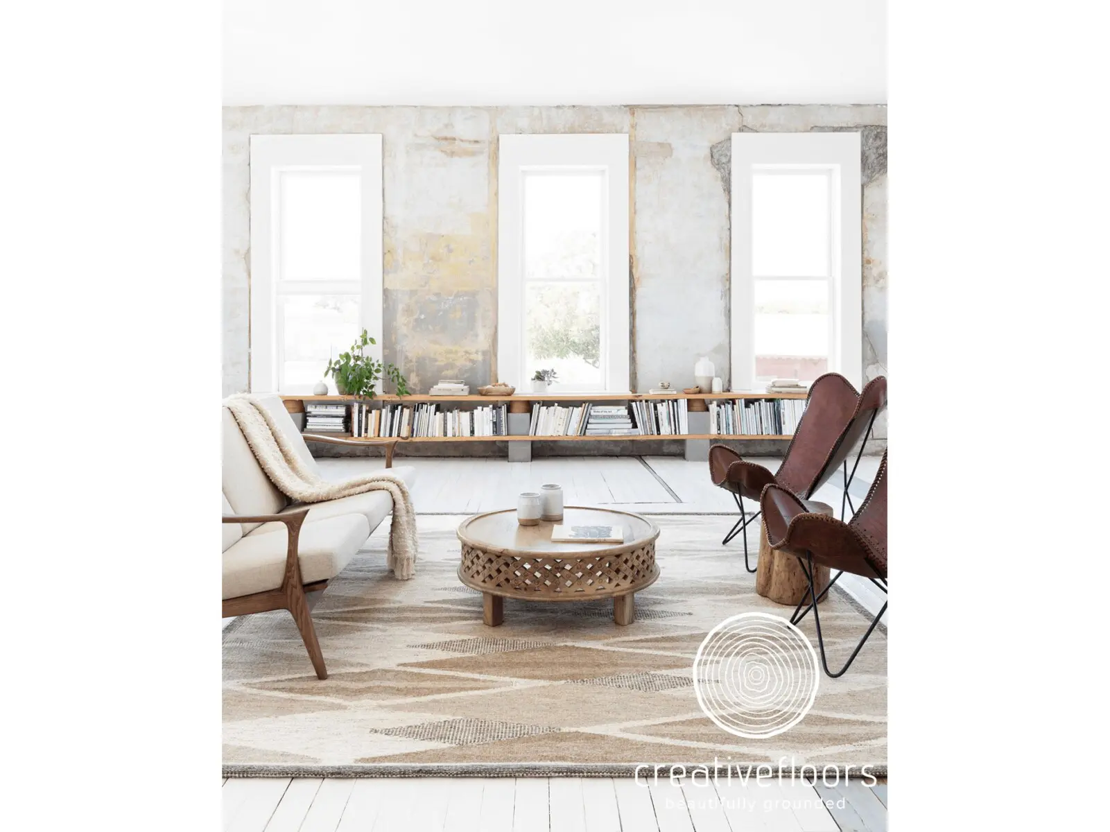 White modern living room with hardwood flooring and stylish furniture, natural light, and a decorative rug.