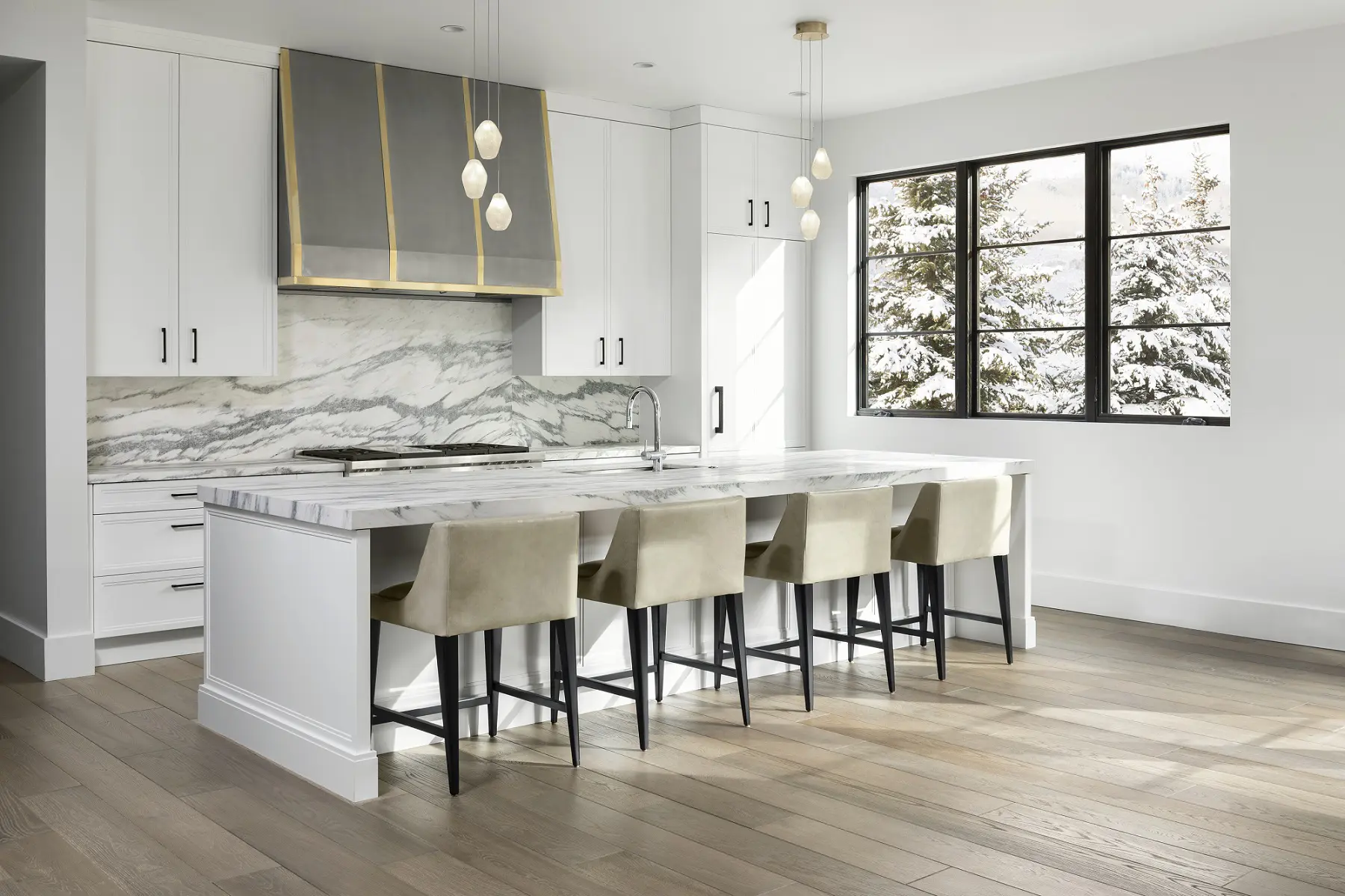 Luxurious white marble kitchen with modern cabinetry and natural light from large windows.