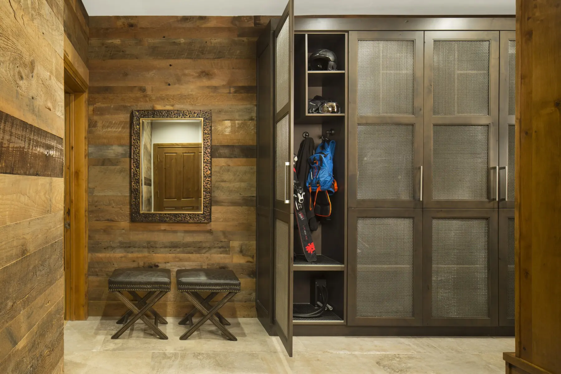 Contemporary mudroom with custom metal and wood cabinetry, offering functional storage solutions for outdoor gear and accessories.