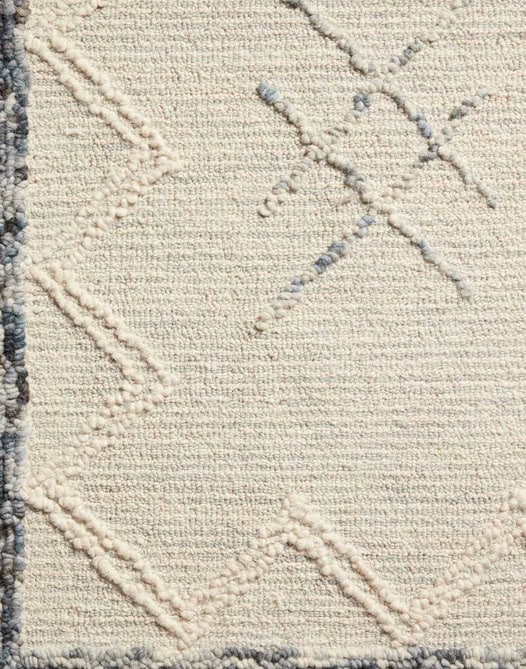 Soft beige textured area rug with geometric embroidery, ideal for stylish home flooring.