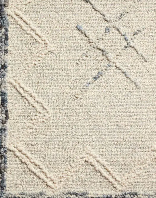 Soft beige textured area rug with geometric embroidery, ideal for stylish home flooring.