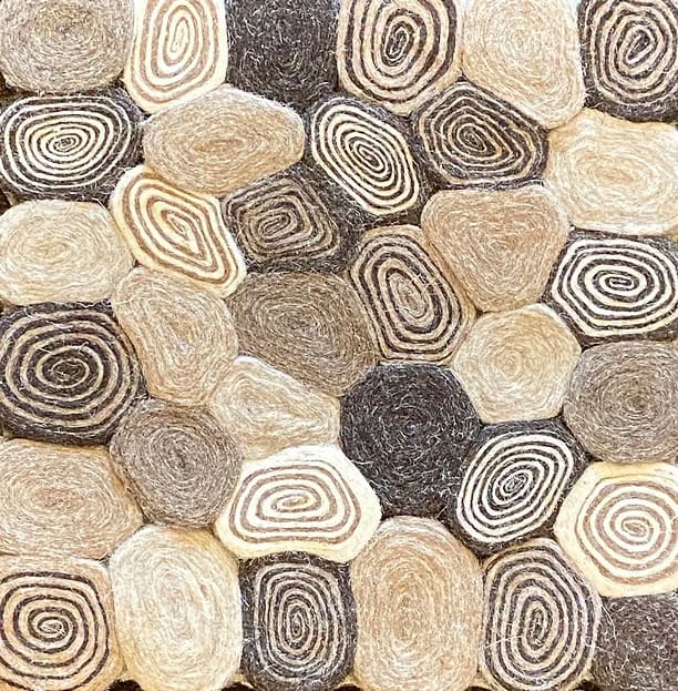 Nature-inspired stone mosaic floor with spiral patterns and neutral tones.
