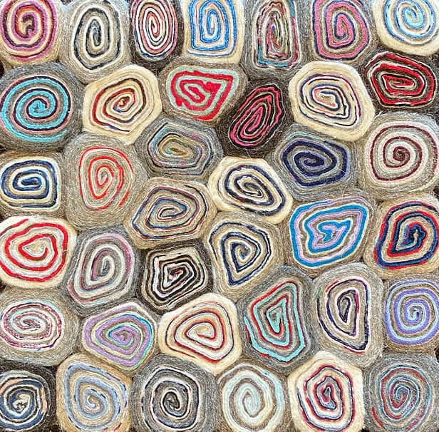 Colorful coiled fiber rugs with vibrant spirals and intricate patterns, perfect for bohemian or contemporary home decor.