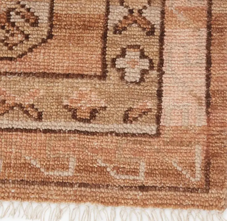 Fine detail of handcrafted traditional Persian rug with intricate patterns and warm earth tone colors.