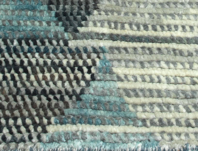 Soft textured woven carpet in neutral tones with hints of blue and grey for interior flooring; high-quality craftsmanship.