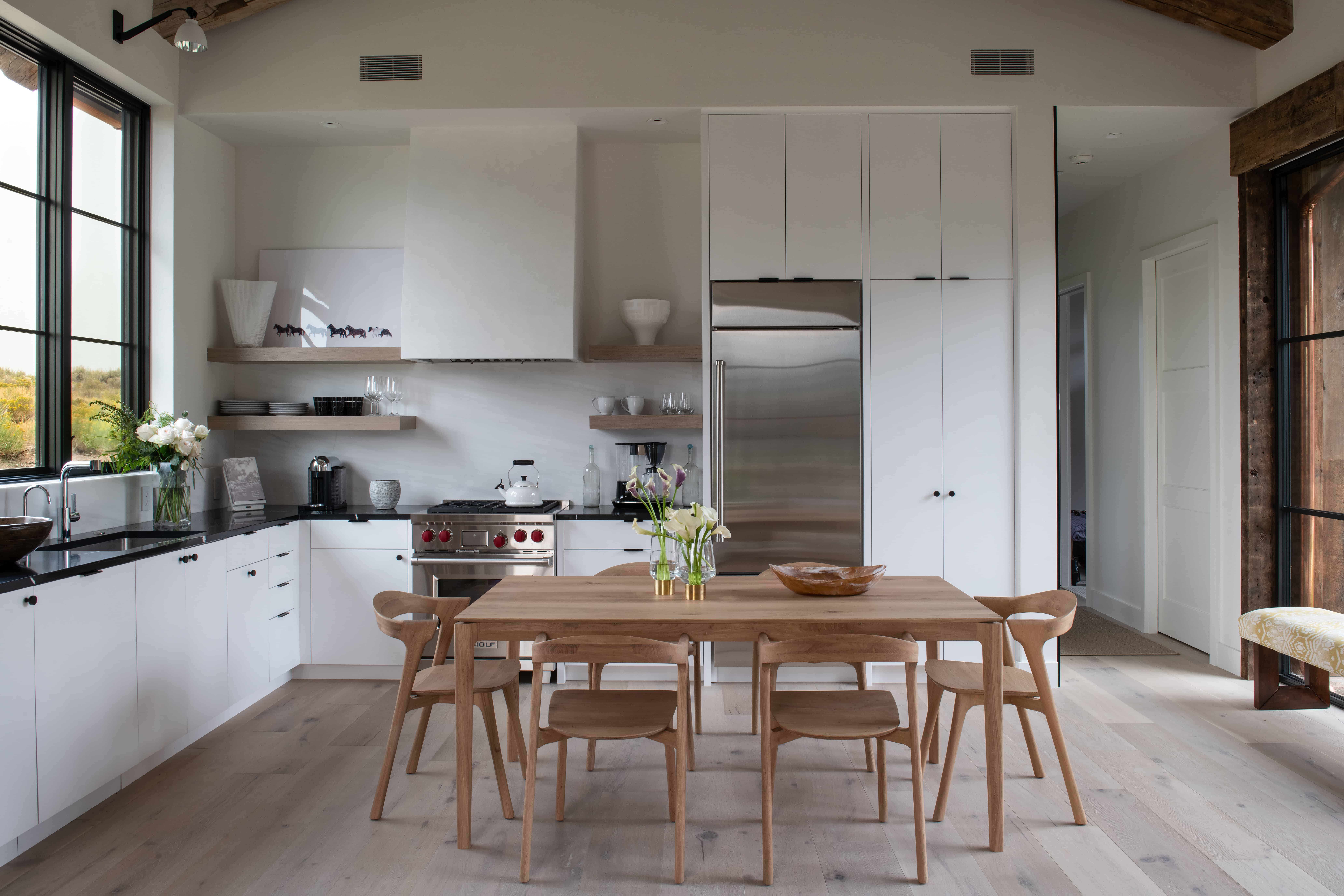 Vinyl plank flooring in modern kitchen with white cabinets and wooden dining table.