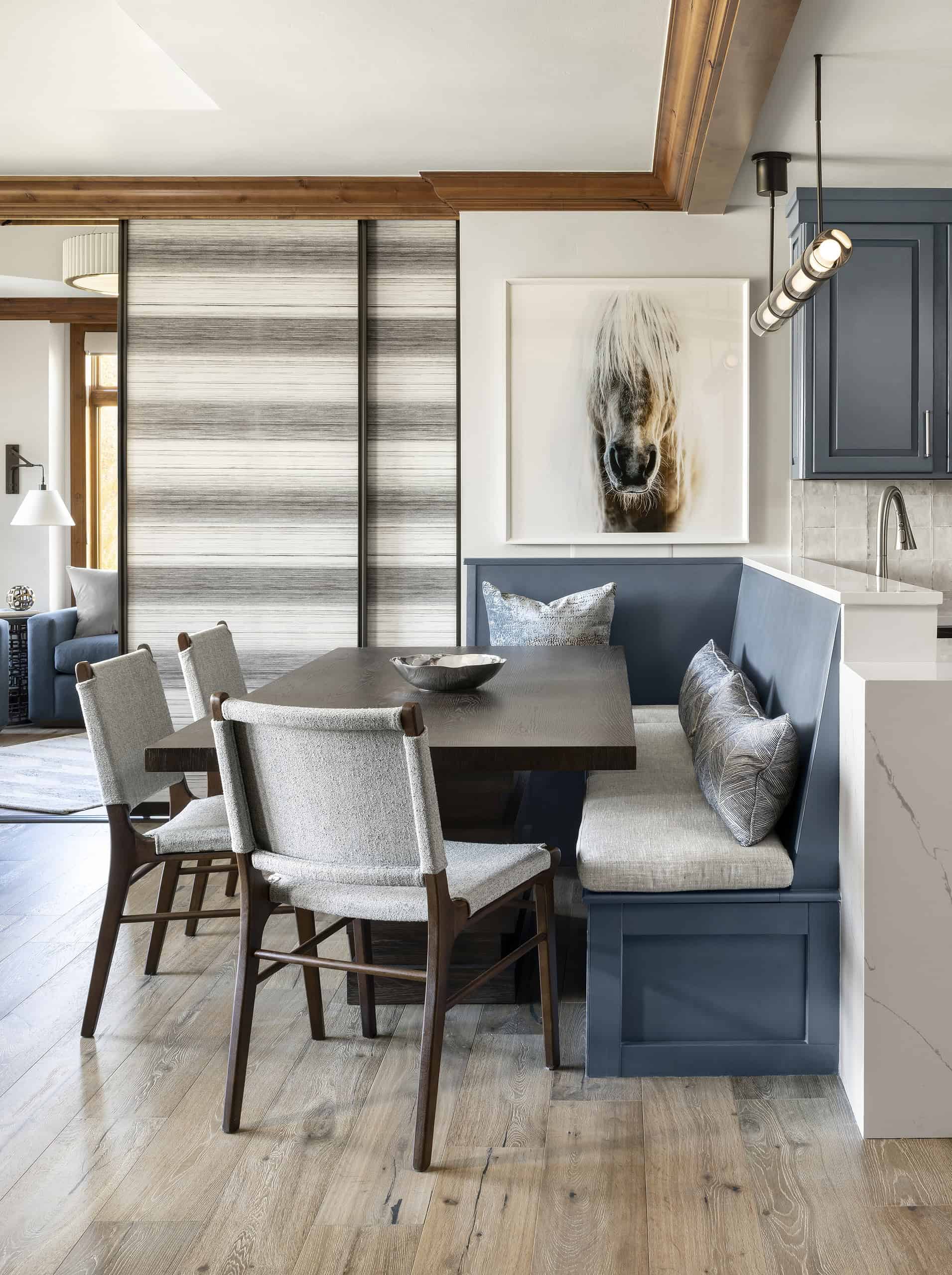 Shaker-style blue kitchen benches with wooden dining table and framed horse artwork.