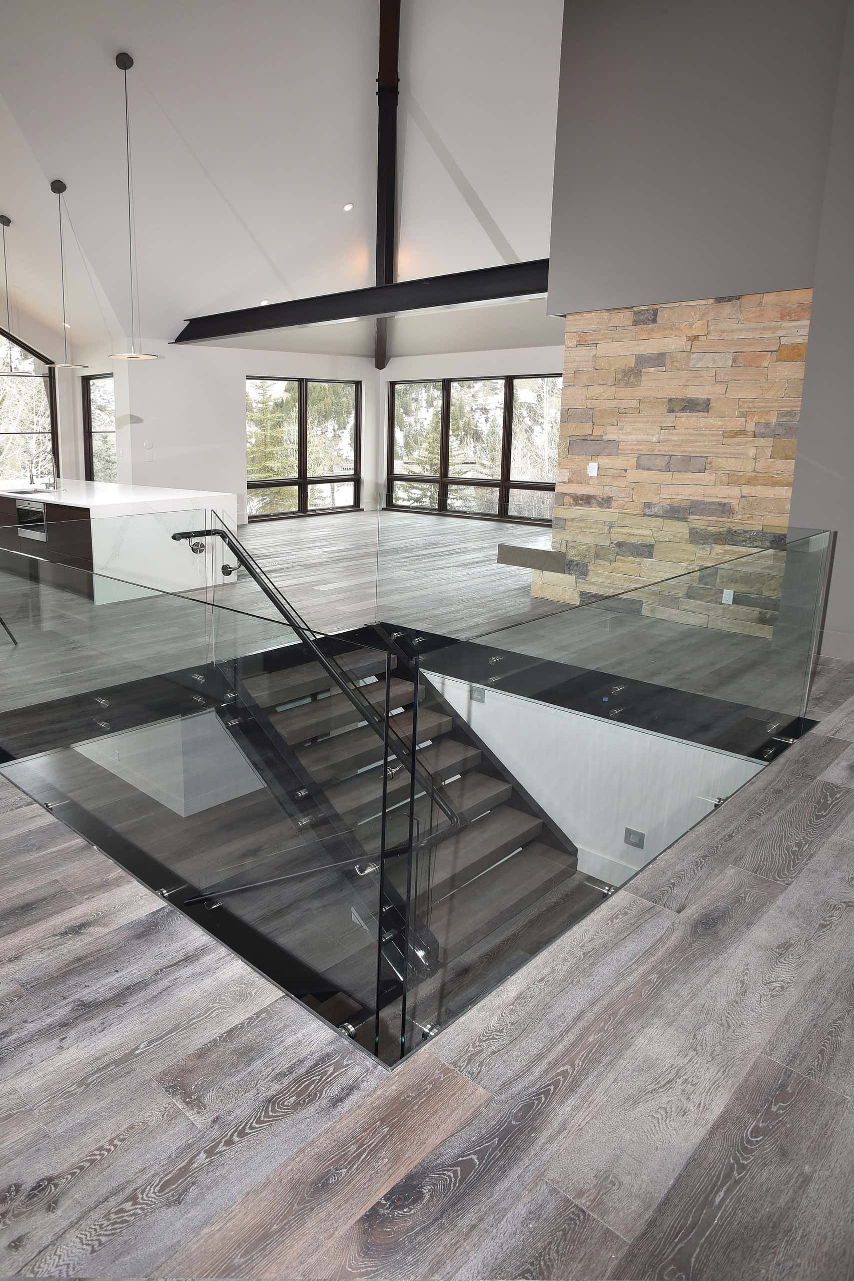 Engineered hardwood flooring with glass stair rail in modern interior.