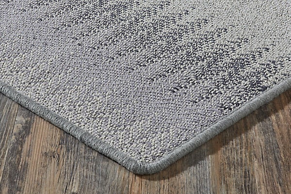 Soft gray textured area rug on hardwood floor in modern interior.
