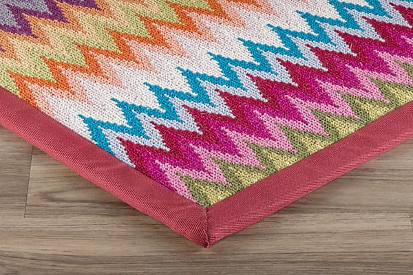 Vibrant geometric patterned rug with colorful zigzag design and durable pink border, perfect for modern interiors.