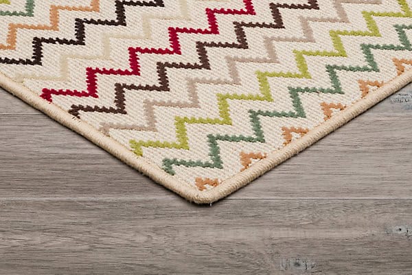 Colorful geometric area rug with zigzag pattern on hardwood floor, perfect for modern home decor.