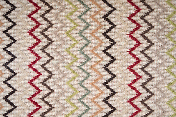 Colorful zigzag pattern area rug with red, black, beige, green, and peach accents.