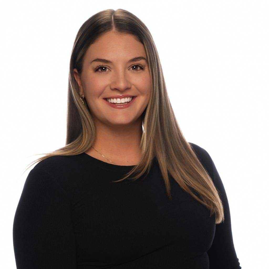 Portrait of a smiling woman with long brown hair in a professional headshot, dressed in a black top, promoting flooring services.