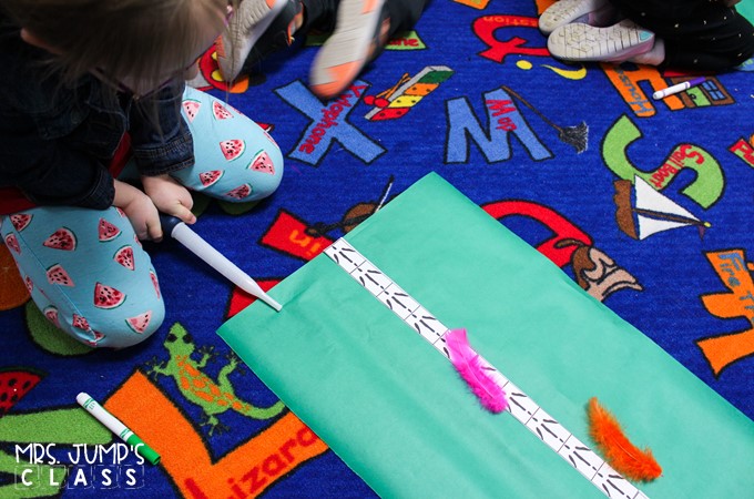 A young girl is using a turkey baster to blow a pink feather down a measurement chart