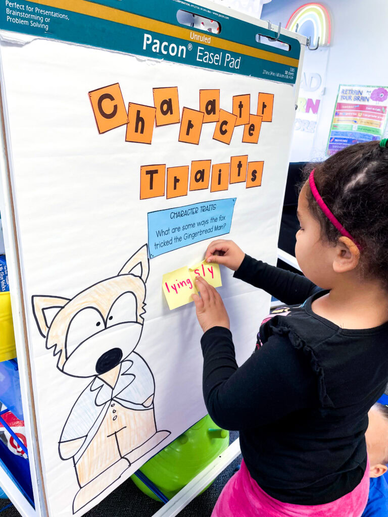 A student adding a sticky note to an anchor chart