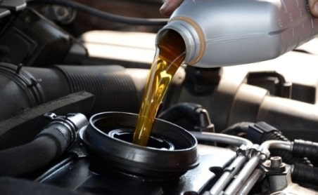 Close-up of engine oil being poured during vehicle maintenance.